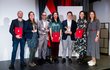 Gruppenfoto der Preisträgerinnen und Preisträger: Sieben Personen stehend teilweise mit roten Urkundenmappen in der Hand