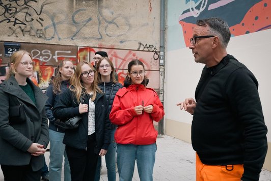 Gruppe junger Menschen hört altem Mann zu