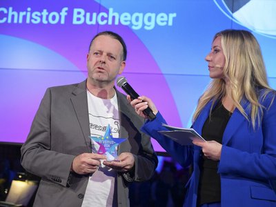 Mann auf Bühne wird von Frau auf Bühne interviewt