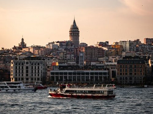 Beeindruckende Aussicht auf die Skyline von Istanbul mit dem ikonischen Galata-Turm und Schiffen bei Sonnenuntergang.