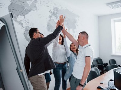 Zwei Männer klatschen in die Hände, zwei Frauen stehen daneben 