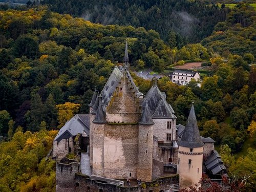 Luftbild einer Burg in Luxemburg in mitten von Wald.