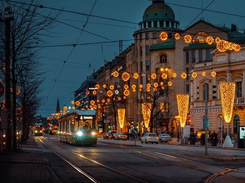 Ein lebendiger Winterabend in Helsinki mit festlichen Lichtern, die die Straßen erhellen, und einer Straßenbahn in Bewegung.