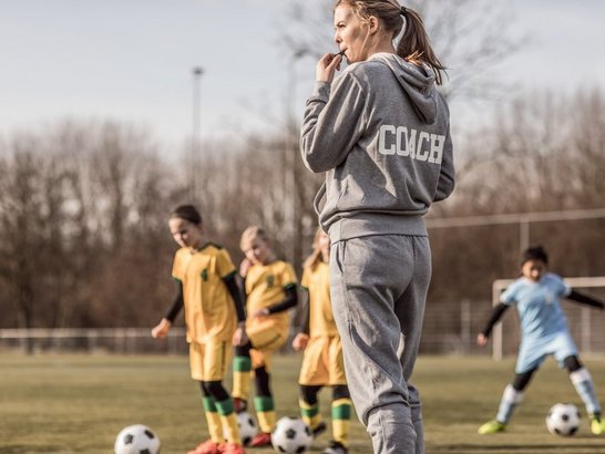 923184844 Trainerin auf Fußballplatz mit jungen Spielerinnen
