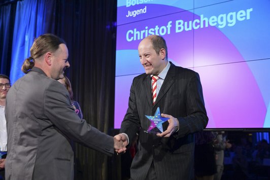 Mann bekommt von anderem Mann Award überreicht 