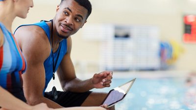 Schwimmtrainer im Gespräch mit Athletin in Schwimmhalle