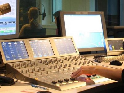 Radio studio with a person's hand operating a mixer.