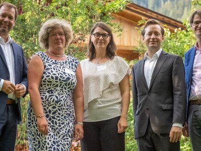 5 Personen (darunter Ernst Gesslbauer, Leiter der Nationalagentur Erasmus+ Bildung und Jakob Calice, Geschäftsführer des OeAD) stehen auf einer Wiese mit grünen Büschen und einem Holzhaus im Hintergrund