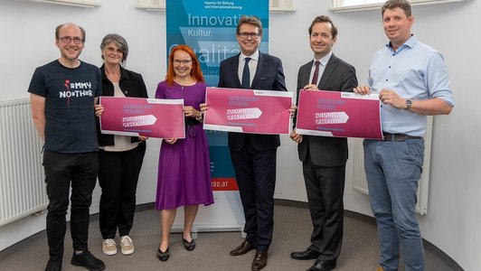 Bildungsminister Martin Polaschek und Wissenschaftler halten ein Schild in die Höhe auf dem Young Science Rocks steht