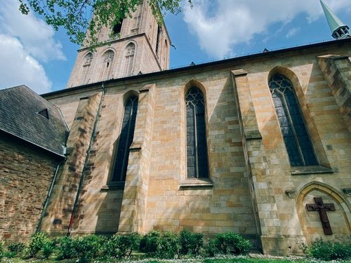 Tiefer Blickwinkel auf eine historische Kirche gegen einen bewölkten blauen Himmel, umgeben von Grün.
