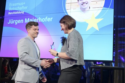 Mann in grauem Anzug erhält Auszeichnung