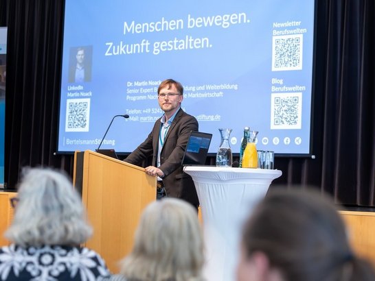 Mann steht am Podium und spricht 