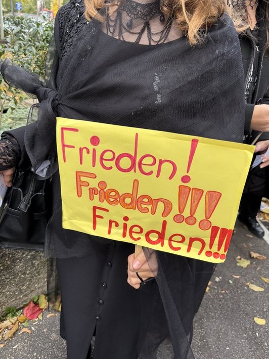 Frieden! Frieden! Frieden!! steht auf einem gelben Schild