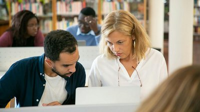 Eine Frau und ein Mann betrachten etwas auf einem Bildschirm.