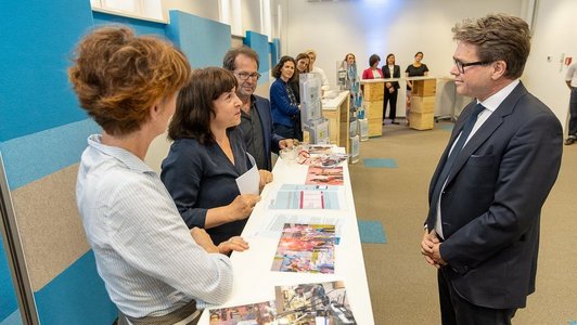 Martin Polaschek im OeAD bei einem Infostand. Eine Dame ist im Gespräch mit ihm.