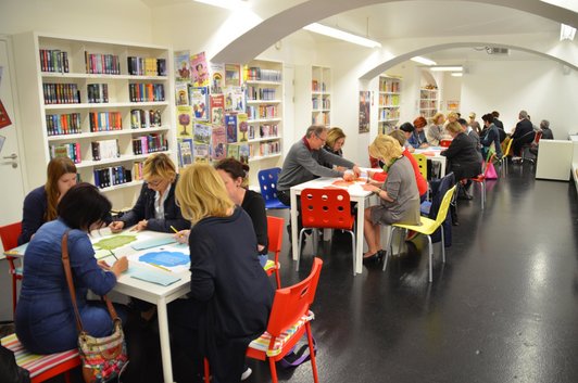 Gruppe an Menschen sitzen in einer Bibliothek und studieren Bücher und Zettel