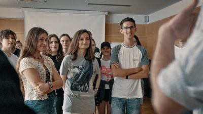 Gruppe junger Menschen steht zusammen und schauen gemeinsam nach vorne zu einer Person die spricht