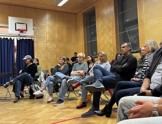 Gruppe im Turnsaal hört Vortrag zu