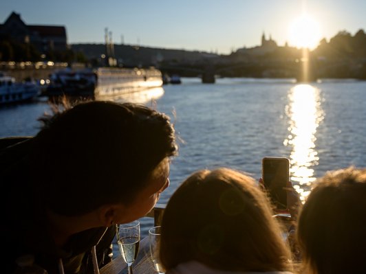 Drei junge Menschen sehen sich den Sonnenuntergang von Bord eines Schiffes an