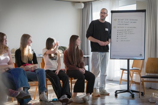 Gruppe junger Menschen hört Mann zu