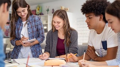 Gruppe von Schüler/innen arbeitet gemeinsam an einem Tisch