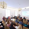 European Year of Skills wie Europass die systematische Dokum Das Bild zeigt eine Europass Veranstaltung. Eine weibliche Person präsentiert vor einem Pult, Veranstaltungsteilnehmer und Teilnehmerinnen hören zu.