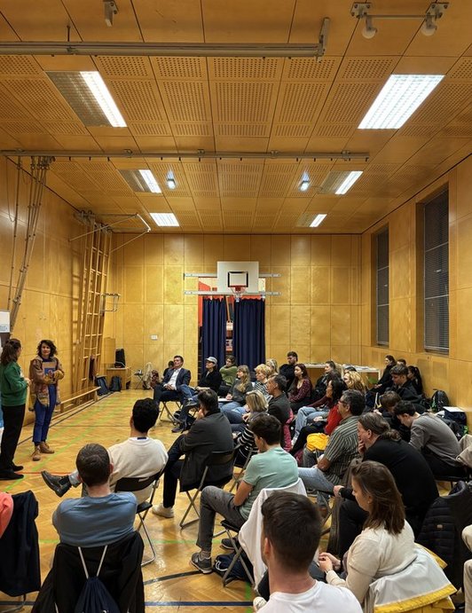 Gruppe im Turnsaal hört Vortrag zu