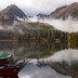 Ruhiger Bergsee mit Booten im nebligen Herbst