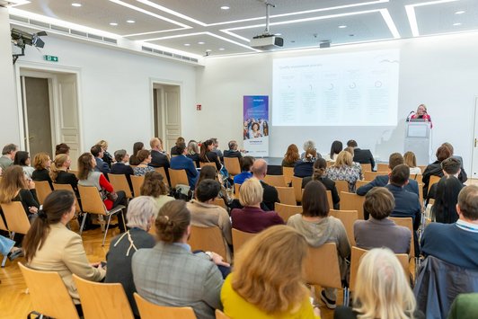 Ein Blick Richtung Bühne zur Präsentation von Trine Tamm über die Köpfe des Publikums hinweg.