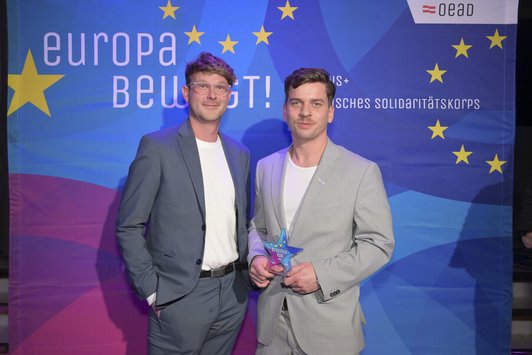 Zwei Männer stehen nebeneinander und schauen in die Kamera 