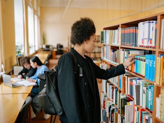 Eine Frau schaut sich Bücher in einer Bibliothek an.