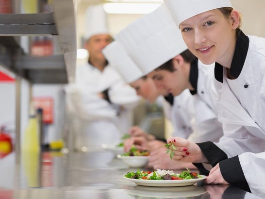 Happy chef looking up from preparing salad in culinary class