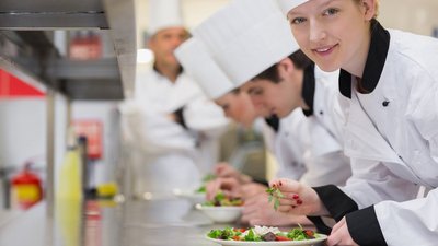 Happy chef looking up from preparing salad in culinary class