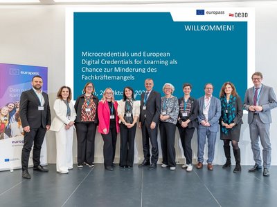 Alle Speaker der Veranstaltung stehen in einer Reihe nebeneinander auf der Bühne vor der Titelbildfolie der Präsentation. 