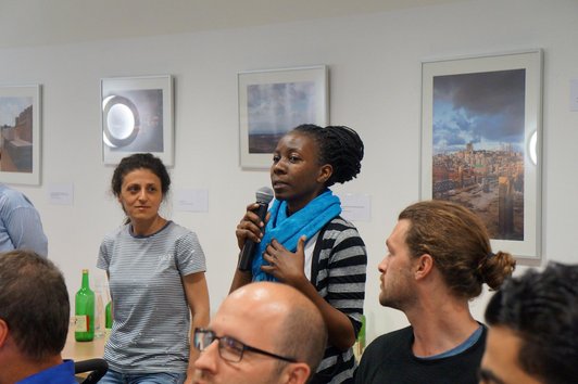 Woman talking into a microphone and other people are looking at her