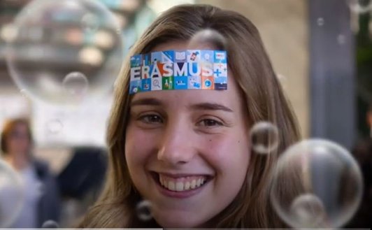 A young smiling woman with an Erasmus+ sticker on her forehead.