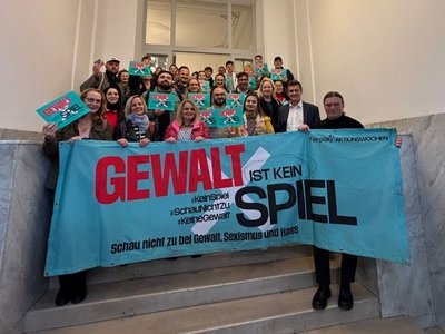 Gruppe an Menschen hält Banner hoch "Gewalt ist kein Spiel"