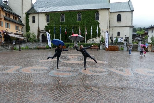 Zwei Schülerinnen steht mit Schirm im Regen