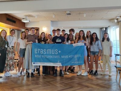 Gruppe junger Menschen hält "Erasmus+" Banner in die Kamera 