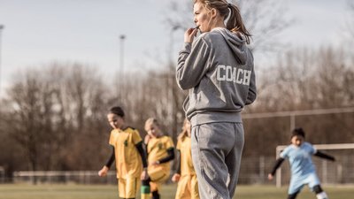 Trainerin auf Fußballplatz mit jungen Spielerinnen