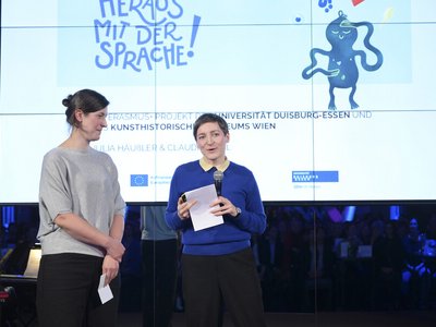 Zwei Frauen stehen auf einer Bühne und präsentieren