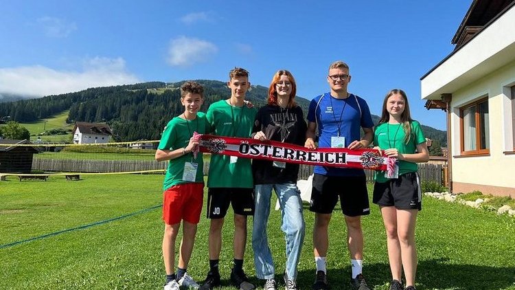 Fünf junge Menschen halten einen Österreich-Schal vor einer Bergkulisse