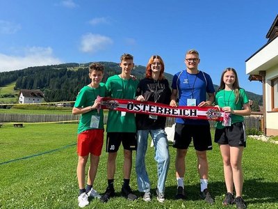 Fünf junge Menschen halten einen Österreich-Schal vor einer Bergkulisse