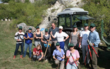 Eine Gruppe junger Menschen steht mit Landmaschinengeräten für einem Traktor und lacht in die Kamera