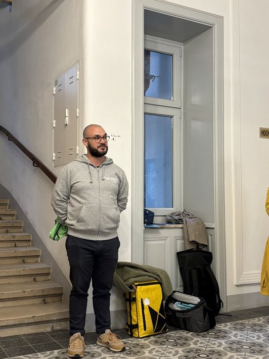 Mann in grauer Jacke mit Brille spricht