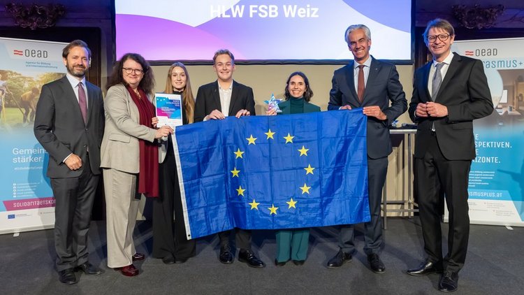 Gruppe von Menschen verschiedenen Alters und Geschlechts in festlicher Kleidung, die EU-Flagge halten