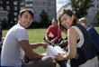  Students sit on the lawn with books and laugh happily