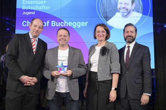 Drei Männer und eine Frau lachen in die Kamera 