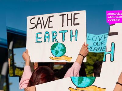 Frau hält Schild mit dem Satz "Save the earth" in die Höhe 