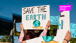 Frau hält Schild mit dem Satz "Save the earth" in die Höhe 